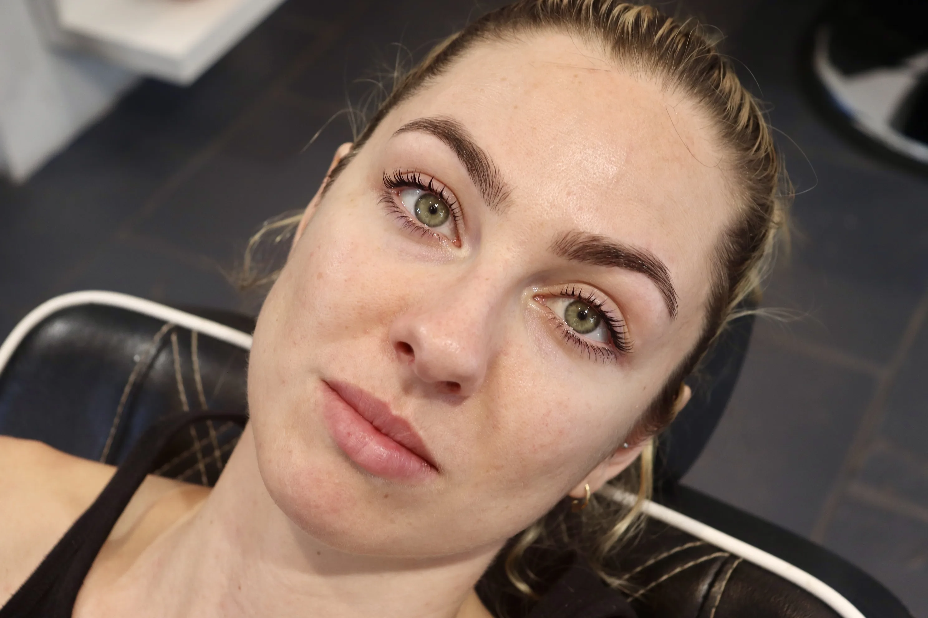 Client looking up from the salon chair, shaped brows and lifted lashes