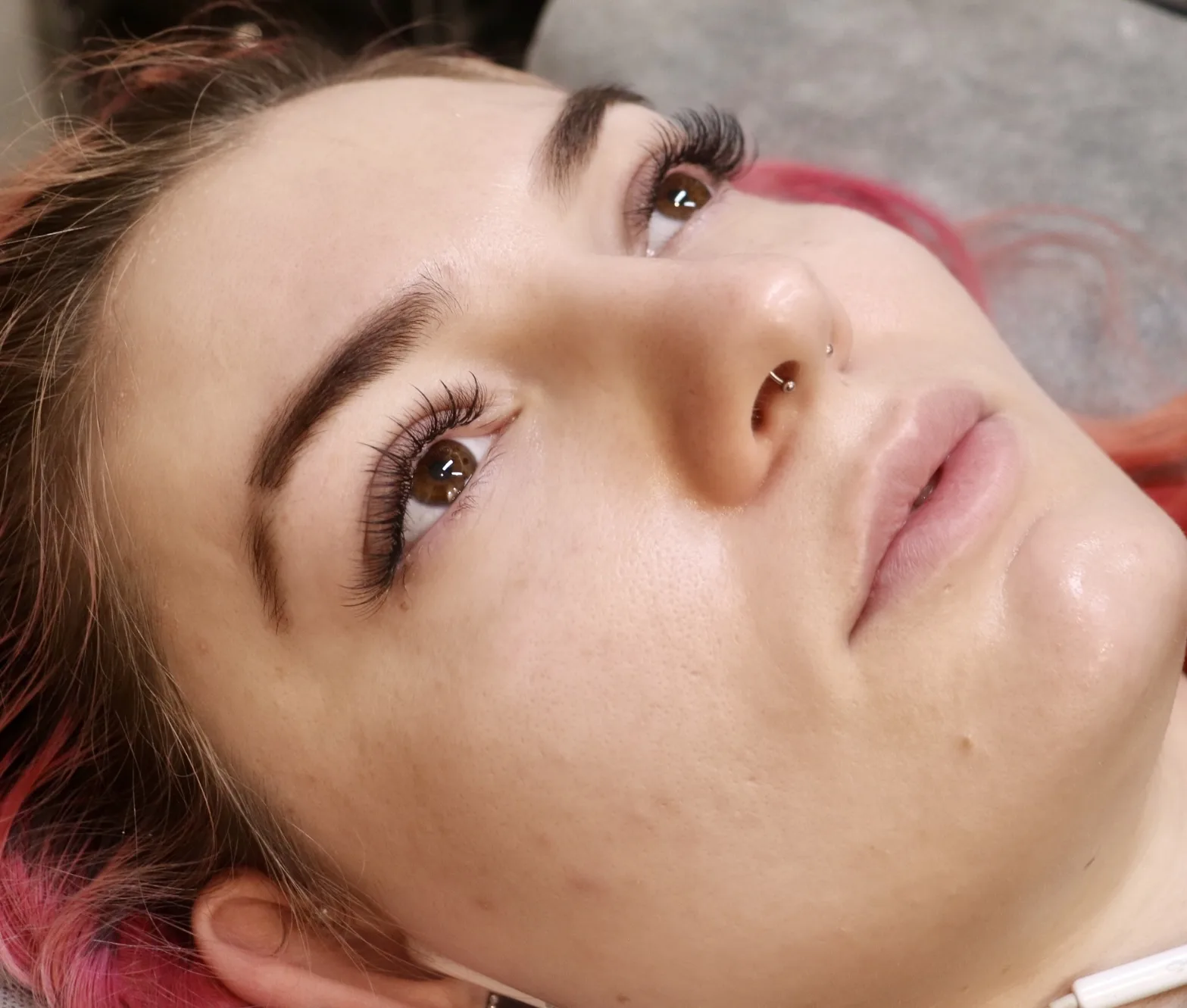 Pink-haired client with a soft natural lash lift and shaped brows