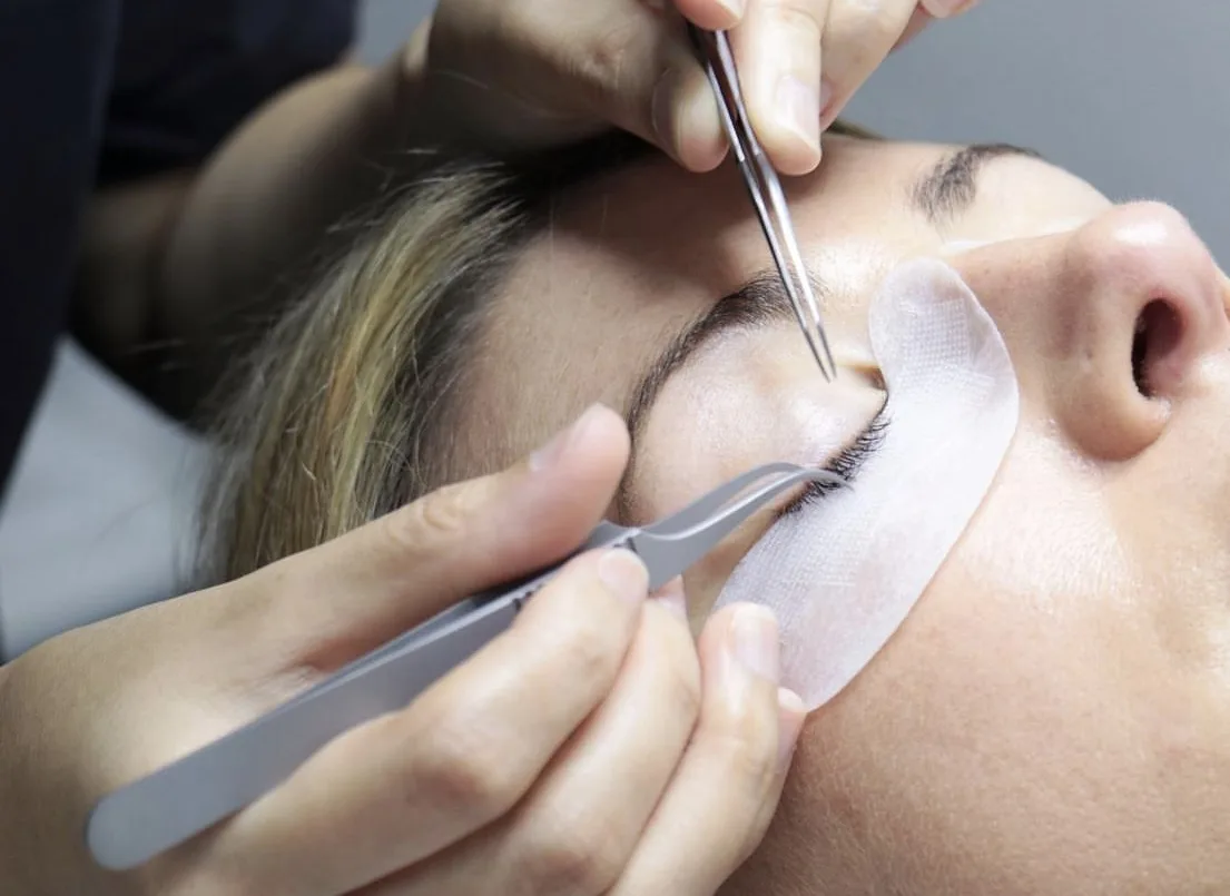 Technician applying lash extensions with isolation and application tweezers