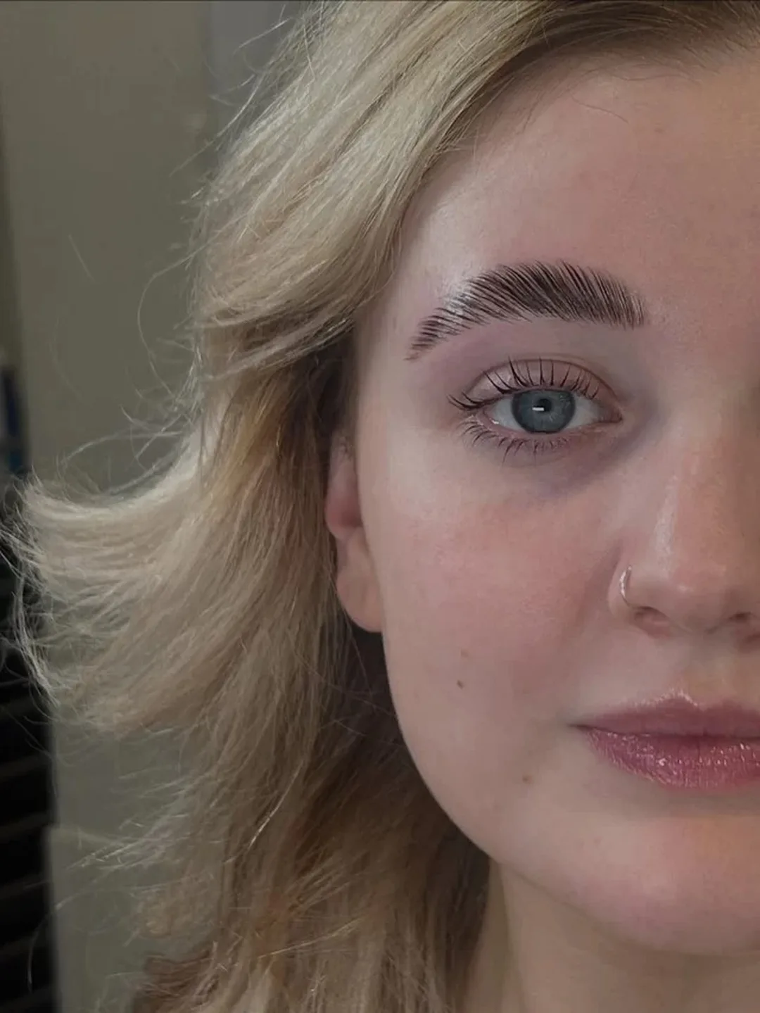 Close portrait of a blonde client with a fluffy groomed brow and lifted lash line