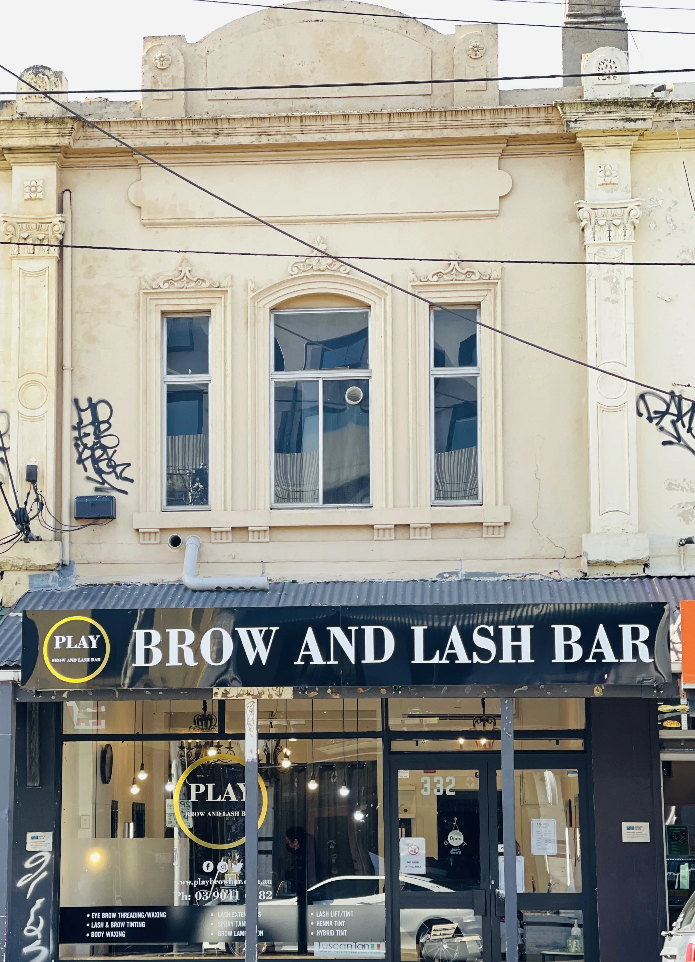 Play Brow and Lash Bar shopfront at 332 Brunswick Street, Fitzroy — black awning, gold ring decal on the window