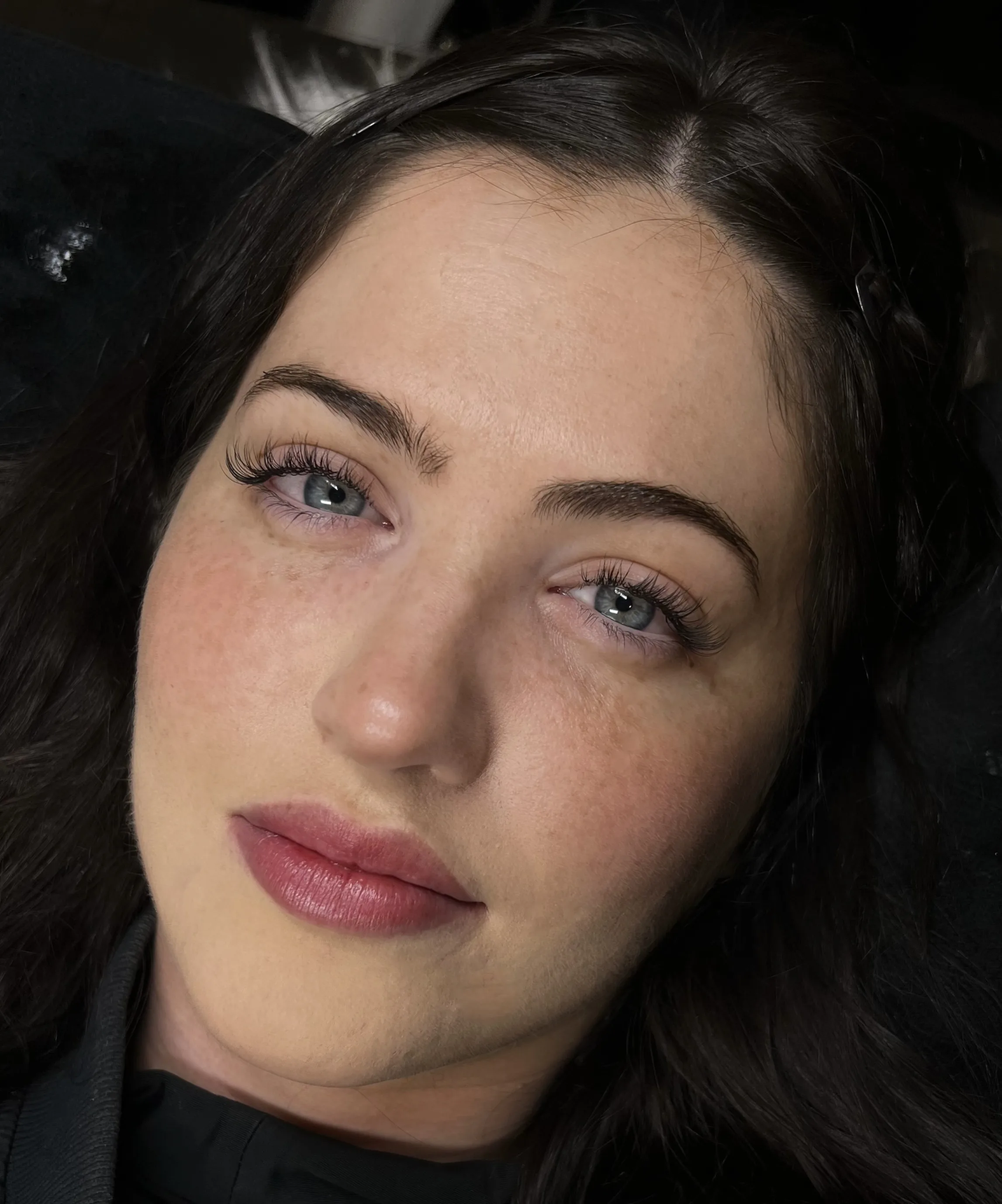 Finished lash extension set, client in low-lit treatment room